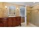 Bathroom vanity featuring a dark wood cabinet, granite countertop, and tiled shower with glass door at 302 Eastleigh Dr, Belleair, FL 33756