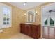 Bright bathroom with a wooden vanity, shutters, and a doorway leading to a sunny room at 302 Eastleigh Dr, Belleair, FL 33756