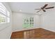 Bright bedroom with hardwood floors, ceiling fan, and white window shutters at 302 Eastleigh Dr, Belleair, FL 33756