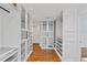 Walk-in closet featuring glass-front cabinets, custom shelving, wood flooring, and modern lighting at 302 Eastleigh Dr, Belleair, FL 33756