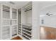 Custom closet design with glass-front cabinets, built-in shelves, and drawers; hardwood floors at 302 Eastleigh Dr, Belleair, FL 33756