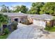 Beautiful brick home boasts an attached garage, large driveway, and professionally landscaped front yard at 302 Eastleigh Dr, Belleair, FL 33756