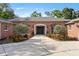 Charming brick home featuring a wide driveway, manicured landscaping, and a welcoming front entrance at 302 Eastleigh Dr, Belleair, FL 33756