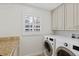 Well-lit laundry room with granite countertops, cabinets, and modern washer and dryer at 302 Eastleigh Dr, Belleair, FL 33756