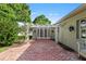 Outdoor patio space featuring brick flooring, white pergola and lush landscaping at 302 Eastleigh Dr, Belleair, FL 33756
