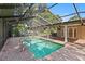Outdoor pool area enclosed by a screen, with brick paving and lush landscaping at 302 Eastleigh Dr, Belleair, FL 33756