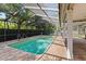 Outdoor pool area enclosed by a screen, surrounded by brick paving and mature trees at 302 Eastleigh Dr, Belleair, FL 33756