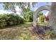 Landscaped backyard featuring mature trees, decorative archway, and view of the nearby lake at 35836 Lakeshore Dr, Dade City, FL 33525