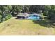 An aerial view of a home with a screened-in pool area surrounded by an expansive lawn and mature trees at 35836 Lakeshore Dr, Dade City, FL 33525