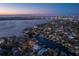 Stunning aerial view of waterfront homes with private docks and city skyline in the background at twilight at 38 Ladoga Ave, Tampa, FL 33606
