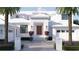 Elegant two-story white home featuring a brick facade, palm trees, a symmetrical design, and a well-maintained walkway at 38 Ladoga Ave, Tampa, FL 33606