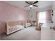 Bedroom room with pink accent wall, two cribs, ceiling fan and window at 403 S Fremont Ave # 3, Tampa, FL 33606