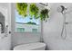 Bright bathroom featuring marble walls, a modern soaking tub, and hanging plants near the window at 4515 W North A St # 6, Tampa, FL 33609