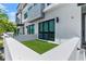 Turfed outdoor patio area with white perimeter wall, a palm tree, and modern architecture at 4515 W North A St # 6, Tampa, FL 33609