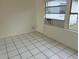 Bright bedroom featuring white tile floors, a window, and an air conditioning unit at 4705 Murray Hill Dr, Tampa, FL 33615