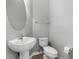 Well-lit half bathroom with a pedestal sink, toilet, and a round mirror at 5015 58Th E Ter, Bradenton, FL 34203