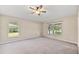 Bright main bedroom featuring neutral carpet, ceiling fan, and large windows with a view of the lake at 5131 Gato Del Sol Cir, Wesley Chapel, FL 33544