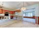 Unfinished kitchen area with wooden cabinets, a microwave, and view to the sunroom with large window at 565 55Th Ne Ave, St Petersburg, FL 33703