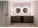 Bathroom featuring dual sinks with illuminated mirrors and a dark wood vanity cabinet with open storage at 777 3Rd N Ave # 1603, St Petersburg, FL 33701