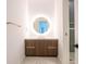 Modern bathroom boasts wood vanity with gray countertop and round mirror with backlight at 777 3Rd N Ave # 1704, St Petersburg, FL 33701