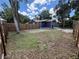 Backyard features a new fence, home with blue siding, green grass, and mature trees providing shade at 8018 Mulberry St, Tampa, FL 33604