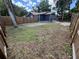 Backyard features a new fence, home with blue siding, green grass, and mature trees providing shade at 8018 Mulberry St, Tampa, FL 33604