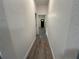Hallway with wood grain vinyl flooring, white walls and black door leading to front of house at 8018 Mulberry St, Tampa, FL 33604