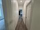 Hallway with wood grain vinyl flooring and white walls with view to bedroom and living room at 8018 Mulberry St, Tampa, FL 33604