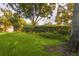 Green backyard featuring a manicured lawn, mature trees, and garden with flowers and shrubs at 803 Brooker Village Cir, Lutz, FL 33548