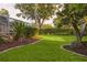 Picturesque backyard featuring lush green grass, landscaped garden beds, and a tranquil setting at 803 Brooker Village Cir, Lutz, FL 33548