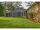 Spacious backyard featuring a screened-in pool, lush green lawn, and well-maintained landscaping at 803 Brooker Village Cir, Lutz, FL 33548