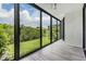 Enclosed sunroom featuring expansive windows with views of lush greenery and modern gray flooring at 900 Cove Cay Dr # 1B, Clearwater, FL 33760
