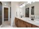 Modern bathroom with dual vanities, white countertops, and an open doorway to the walk-in closet at 10305 Cross River Trl, Parrish, FL 34219