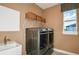Functional laundry room with modern washer and dryer, a sink, and storage baskets at 10305 Cross River Trl, Parrish, FL 34219