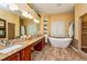 Bathroom featuring double sinks, granite countertop, bathtub, walk-in shower, and a large mirror at 10532 Plantation Bay Dr, Tampa, FL 33647