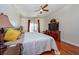 Bright bedroom featuring queen bed, hardwood floors, ceiling fan, and a wooden dresser with television at 10532 Plantation Bay Dr, Tampa, FL 33647