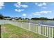 Backyard view showcasing the white picket fence and serene lake beyond, offering a peaceful outdoor setting at 12826 French Market Dr, Riverview, FL 33579