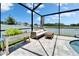 Enjoy the serene lake view from this screened patio with comfortable seating and stylish gray stone flooring at 12826 French Market Dr, Riverview, FL 33579