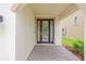 Home entryway featuring a dark front door with glass panels, complemented by stone pavers and exterior walls at 13299 Wildgrass Trl, Odessa, FL 33556