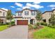 Charming two-story home showcasing a paved driveway, complemented by a well-manicured lawn and a garden area at 13299 Wildgrass Trl, Odessa, FL 33556