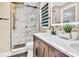 Bathroom featuring double sinks, wood cabinets, and a walk-in shower with marble tile at 1384 S Hillcrest Ave, Clearwater, FL 33756