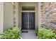 Elegant double front doors surrounded by stone accents and lush greenery at 14514 Woodland Spur Dr, Lithia, FL 33547