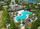 Aerial view of the neighborhood resort-style community pool and amenity center with lush landscaping, lake and homes nearby at 15505 Wicked Strong St, Sun City Center, FL 33573