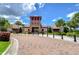 View of the clubhouse with a red brick entrance, a tower, surrounding trees and a beautiful brick laid entrance at 15505 Wicked Strong St, Sun City Center, FL 33573
