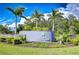 Landscaped entrance to The Vines at Cypress Creek features a stone and stucco sign surrounded by tropical plants and palm trees at 15505 Wicked Strong St, Sun City Center, FL 33573