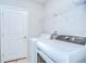 Bright laundry room with white washer and dryer plus overhead storage shelving at 15505 Wicked Strong St, Sun City Center, FL 33573