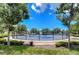 Fenced pickleball court surrounded by trees, offering a shaded and private recreational space in a residential community at 15505 Wicked Strong St, Sun City Center, FL 33573
