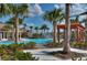 A view of the community pool with palm trees, lounge chairs and clear blue skies with a view of the splash pad at 15505 Wicked Strong St, Sun City Center, FL 33573