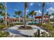 A view of the community pool surrounded by palm trees and a light colored walking path with lounge chairs and cabanas at 15505 Wicked Strong St, Sun City Center, FL 33573