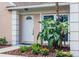 Inviting front entrance with a white door, garden beds with tropical plants, and manicured mulch ground cover at 1621 Crossridge Dr, Brandon, FL 33510
